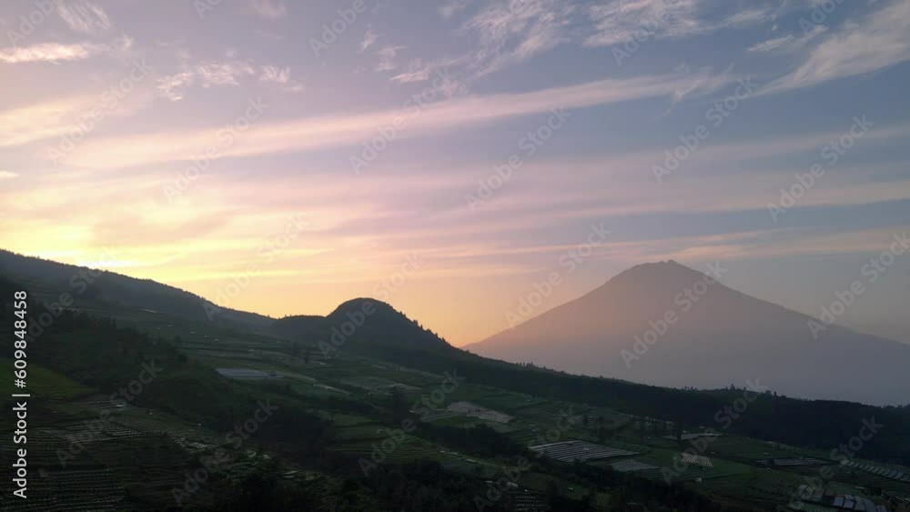 Aerial view of beautiful clouds formation in sunrise sky with huge mountain in the horizon. sunrise over countryside of Indonesia with Mount Sumbing, WONOSOBO, CENTRAL JAVA - 4K drone shot Aerial view of beautiful clouds formation in sunrise sky with huge mountain in the horizon. sunrise over countryside of Indonesia with Mount Sumbing, WONOSOBO, CENTRAL JAVA - 4K drone shot