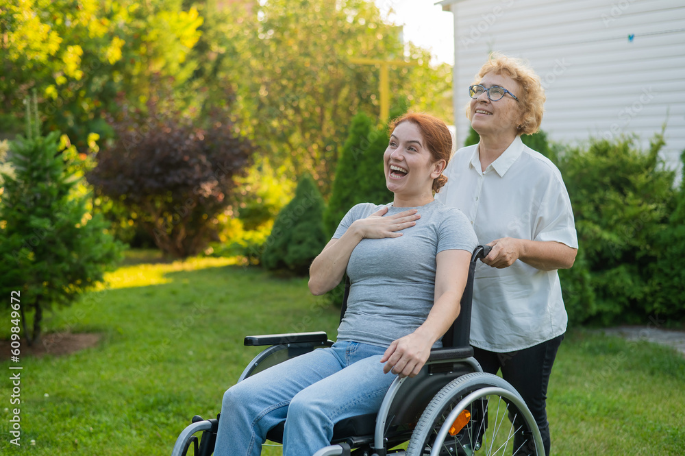 An elderly woman is carrying an adult daughter sitting in a wheelchair. Walk outdoors. An elderly woman is carrying an adult daughter sitting in a wheelchair. Walk outdoors.