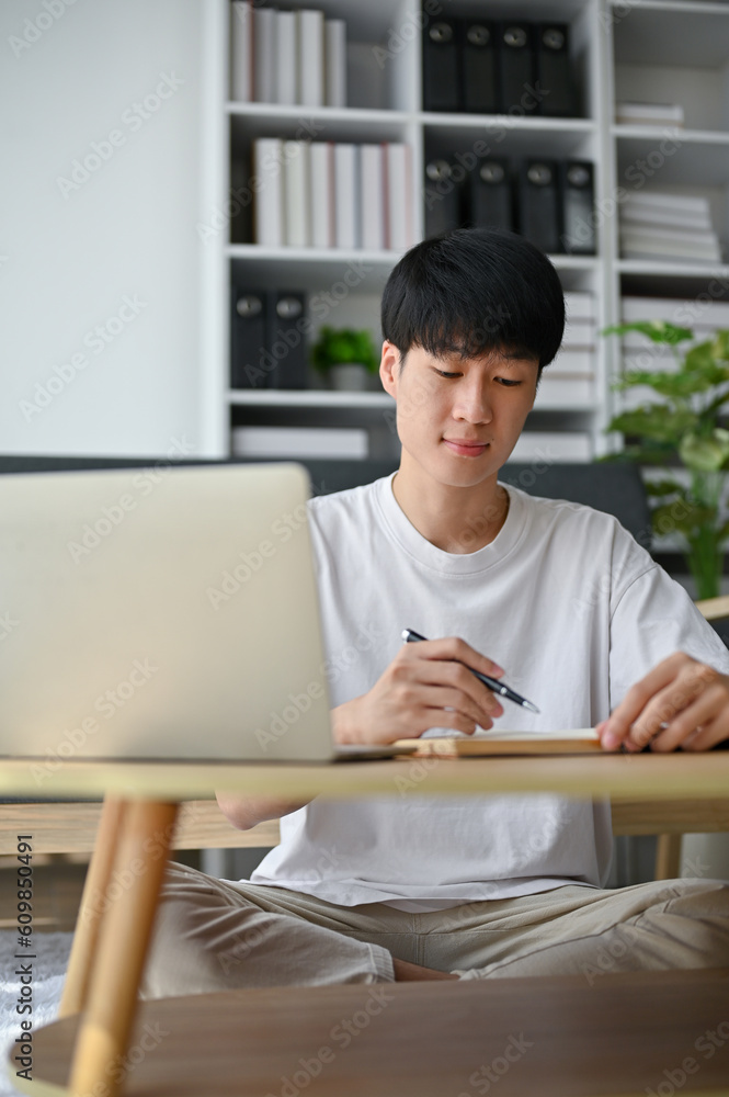 A smart and focused young Asian man is working from home, managing his work A smart and focused young Asian man is working from home, managing his work
