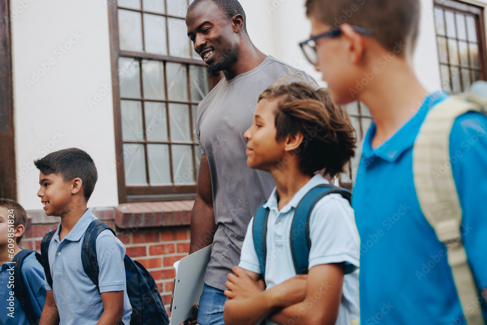 Male school teacher walking outside class with his students Male school teacher walking outside class with his students