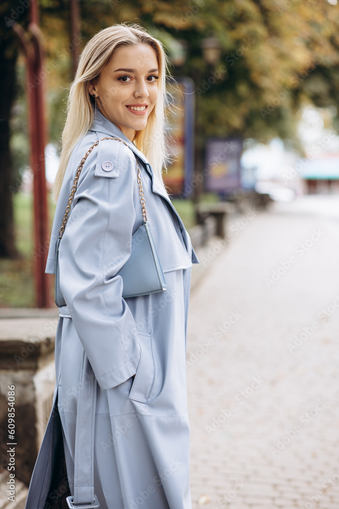 Fototapeta premium Woman in blue coat walking in park