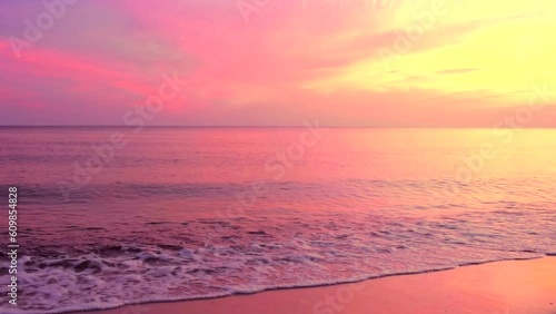 Beautiful sea coast with reflection of pink sunrise light on the colors  purple and yellow sky background. Calm shore waves scene, by the beach with clouds, slow motion, hd. ProRes 422 HQ.