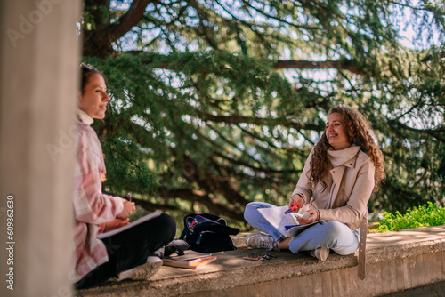 Two girls writing homework together after school and have fun conversation