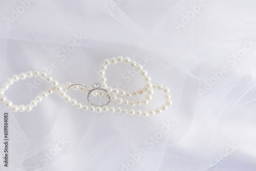 A chic background for wedding design. An elegant white pearl necklace and two white gold diamond engagement rings.
