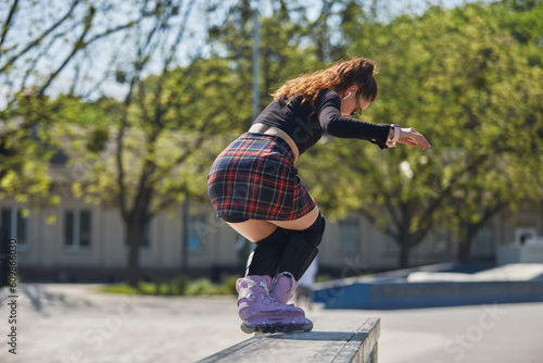 Young skater grinding on a ledge in a skatepark. Cool female roller blader in aggressive inline skates performing a ao pornstar trick photo