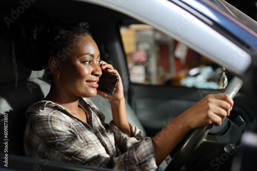 Portrait of happy afirican woman with smiling face driving car vehicle while using smart mobile phone on the road outdoor