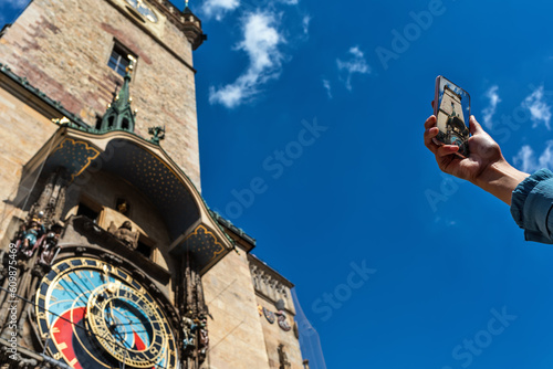 Unidentified person with a smartphone in the hand takes pictures of the astronomical clock in Prague. photo