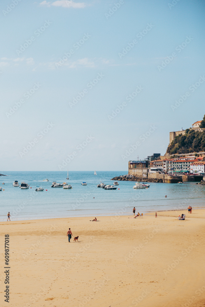 Crowd of people enjoying summer holiday on sandy La Concha beach against apartment buildings on sunny day in Donostia San Sebastian, Basque Country, Spain