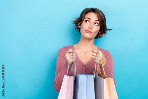 Photoshoot of young minded woman hold shopping bag look thinking empty space guess what inside package isolated on blue color background