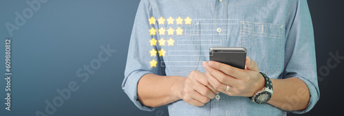 Man holding smartphone device and touching screen with five star rating feedback