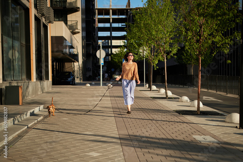 Young pretty female adult with small ginger dog in the bi city walking having fun. City view High quality photo © boytsov