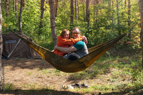 Couple man and woman having fun in a hammock Funny hugs. They laugh and have a good mood, love. Outdoor recreation. Date. Camping tent