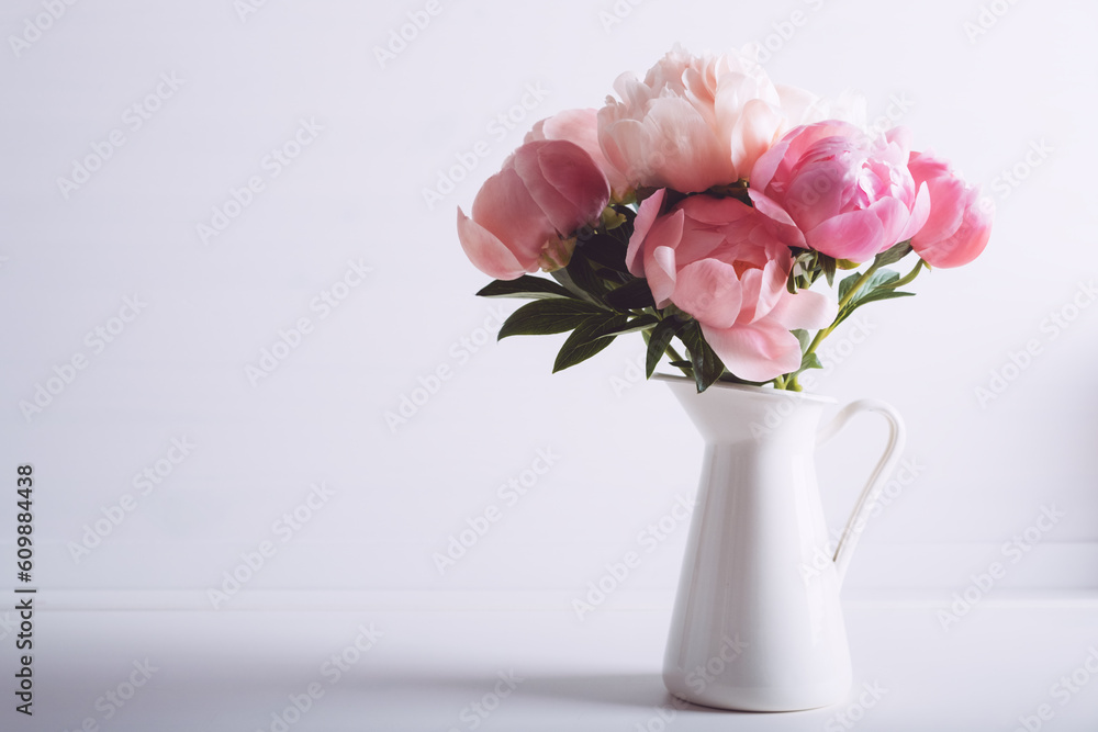 Beautiful bouquet of fresh coral peony flowers in full bloom in vase. Floral still life with blooming peonies. Negative space for text.