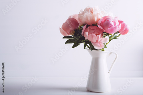 Beautiful bouquet of fresh coral peony flowers in full bloom in vase. Floral still life with blooming peonies. Negative space for text.