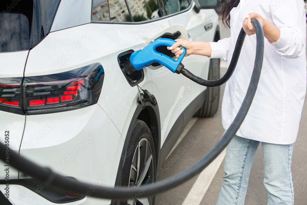 Young business woman refueling her electric car at a EV charging station. Concept of environmentally friendly vehicle. Electric car concept. Green travelling. Young business woman refueling her electric car at a EV charging station. Concept of environmentally friendly vehicle. Electric car concept. Green travelling.