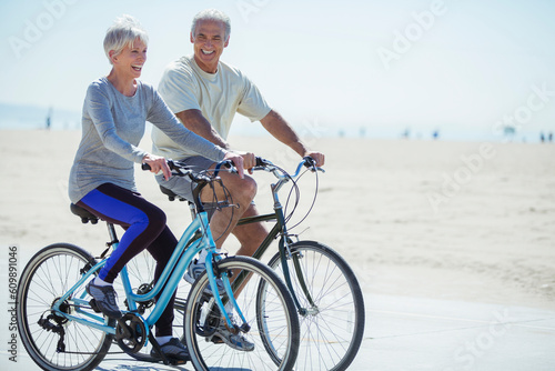 Obraz na płótnie Senior couple riding bicycles on beach boardwalk
