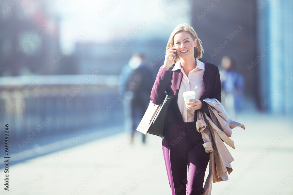 Fototapeta premium Businesswoman talking on cell phone on city sidewalk