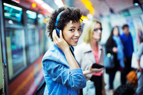 Canvas Print Smiling woman listening to headphones in subway