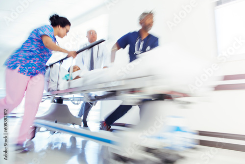 Fotografie Doctors and nurse rushing patient in stretcher in hospital corridor