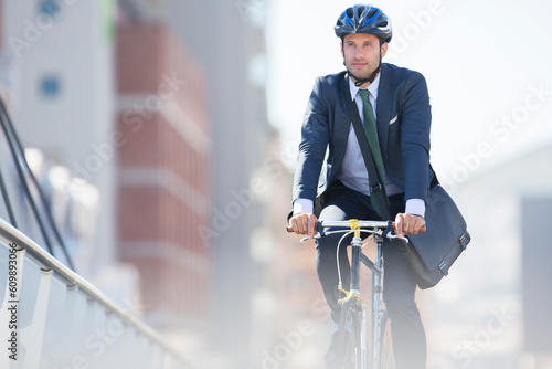 Businessman in suit and helmet riding bicycle in city