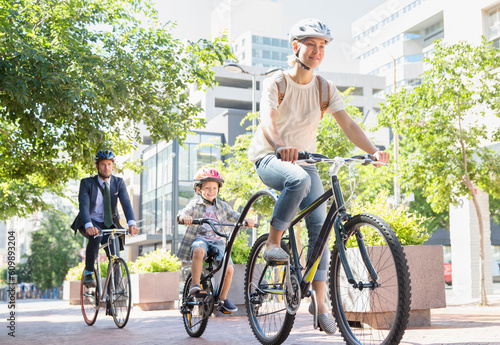 Foto Mother and son in helmets riding tandem bicycle in urban park