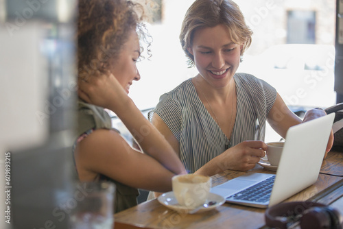 Businesswomen with coffee working at laptop in cafe