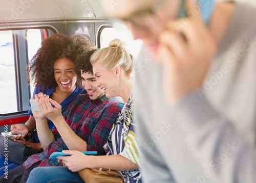 Friends texting with cell phone on bus