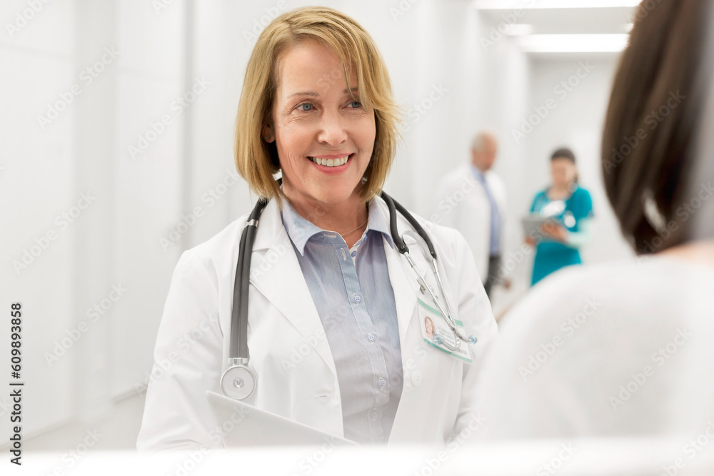 Smiling doctor talking to patient in hospital corridor Smiling doctor talking to patient in hospital corridor
