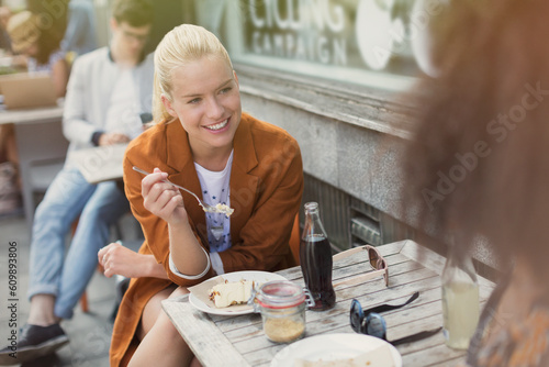 Smiling blonde woman eating dessert at sidewalk cafe