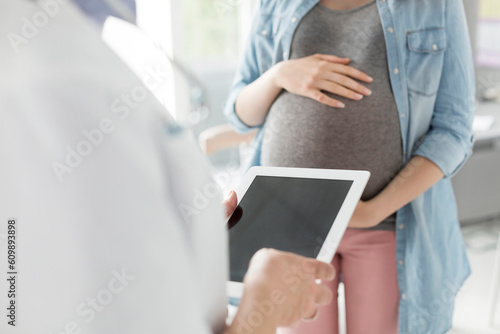 Doctor with digital tablet talking to pregnant patient