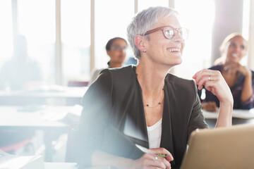 Smiling senior woman at laptop in adult education classroom