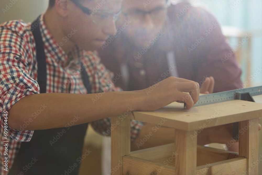Fototapeta premium Focused carpenters measuring wood with ruler in workshop