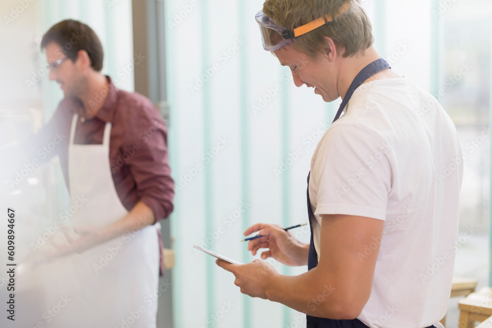 Fototapeta premium Carpenter reviewing notes in workshop