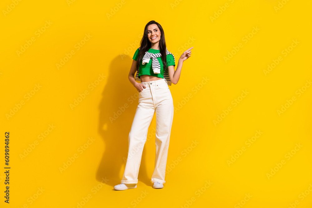 Full length photo of cool hipster girl model wear street clothes direct finger new shopping center isolated yellow color background Full length photo of cool hipster girl model wear street clothes direct finger new shopping center isolated yellow color background