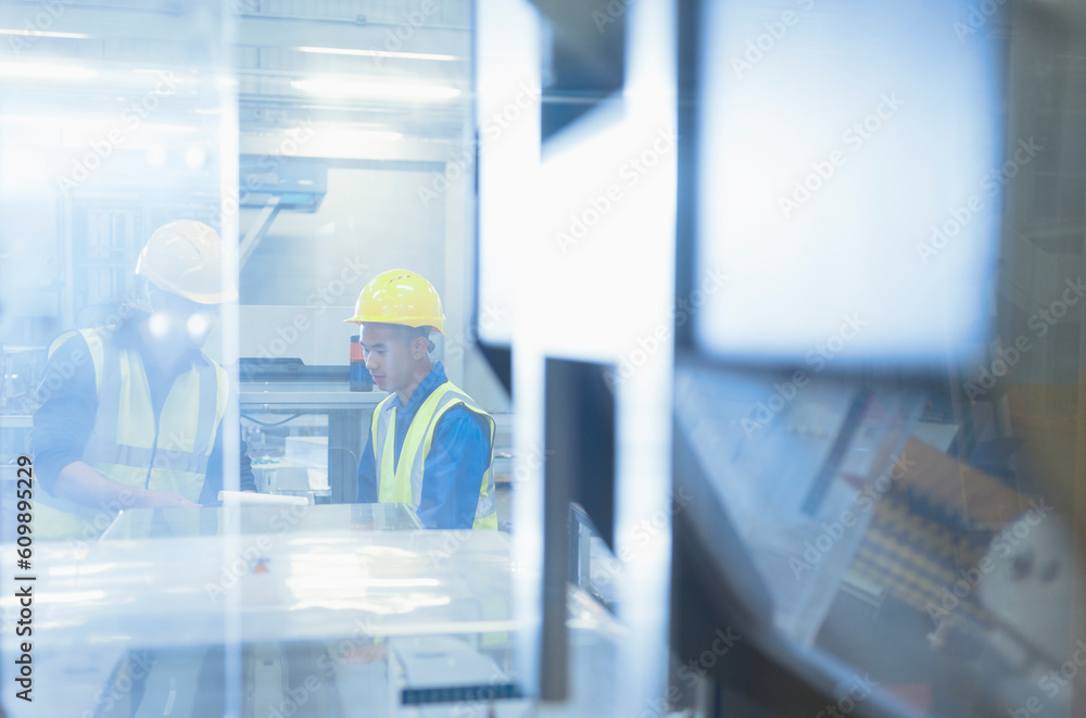 Fototapeta premium Workers talking at machinery in factory