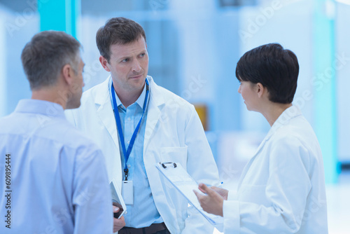 Scientists and businessman talking in factory