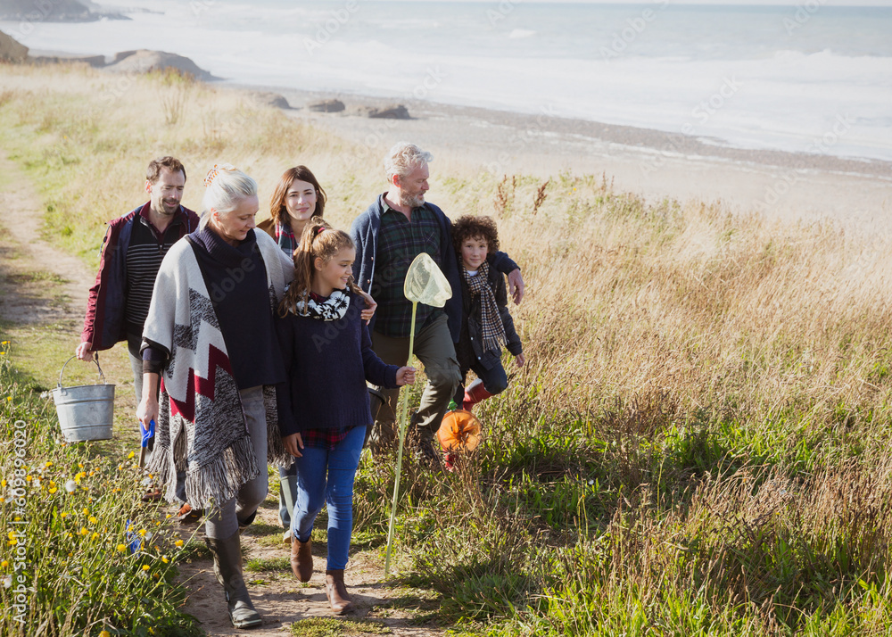 Multi-generation family walking nets bucket on sunny grass beach path - obrazy, fototapety, plakaty 