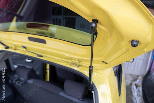 selective focus on the black bar hydraulic hinge supports on the trunk door. soft focus