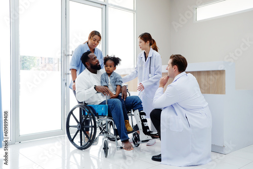 Doctor caring for a patient with a broken leg sitting in a wheelchair. © krongthip