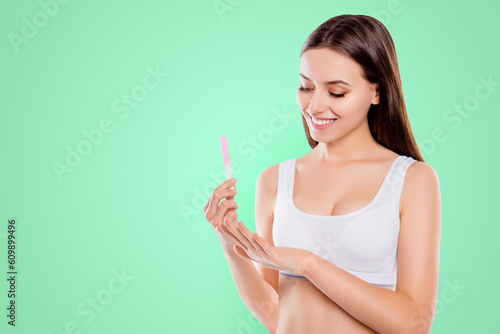 Portrait with copyspace of attractive pretty woman doing manicure looking at fingers filing shaping nails with emery board isolated over white background photo