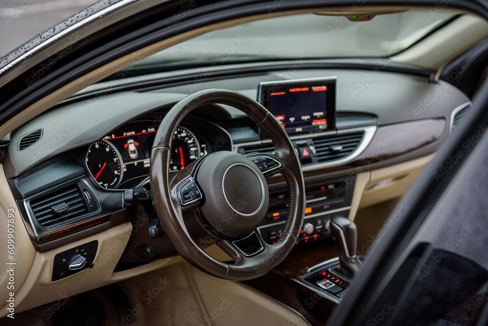 Luxury modern car interior. Steering wheel, shift lever, speedometer, display, gearbox handle, and multimedia dashboard. Detail of car interior inside. Automatic gear stick.