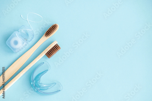 Bamboo toothbrushes  dental floss  mouthguards on a blue background. View from above. Flat lay. Hygiene and dental care concept