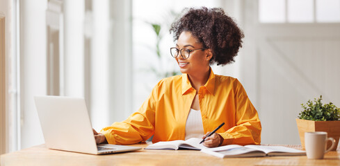 beautiful smiling ethnic woman  works remotely on laptop from home.