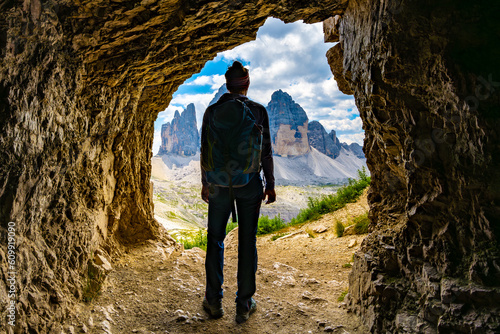 Quadro su tela Young athletic woman enjoys view on Tre Cime mountain range from a small caveat noon