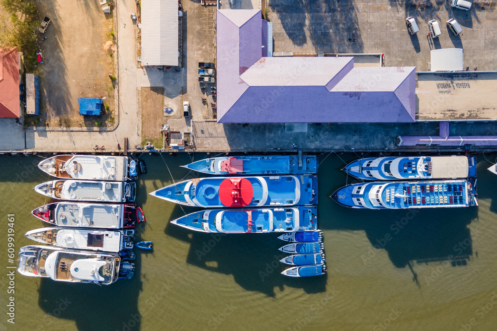 Aerial view of tour boats moored at marina with port building nearby. Top view from drone of motorboats in dock at phuket, Thailand. Nautical vessel transportation business and marine tourism