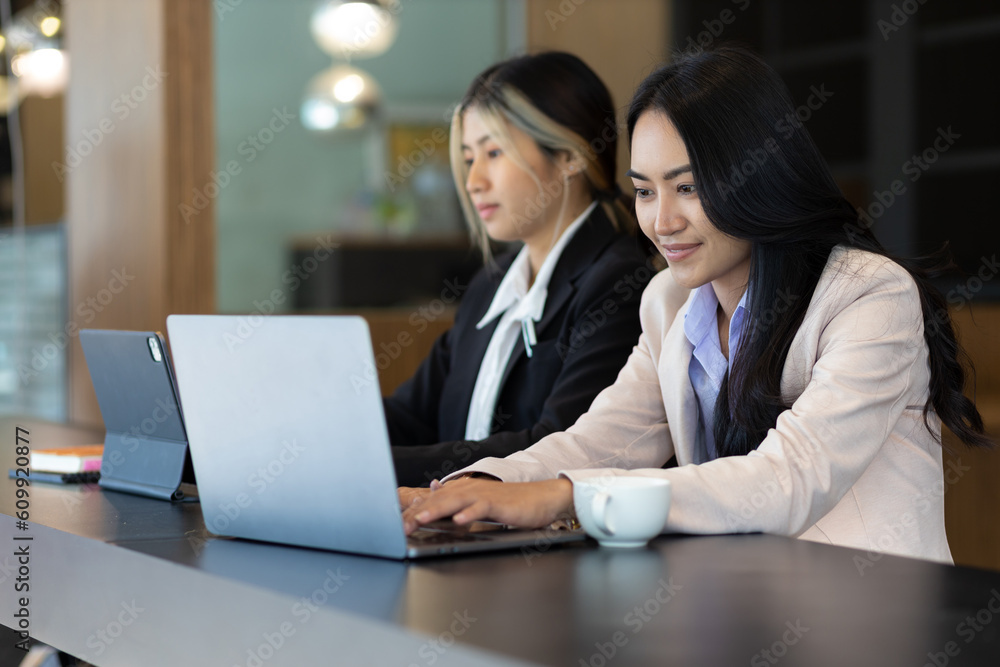 Businesswoman secretary colleague working with laptop in office. Two receptionists work at the counter.