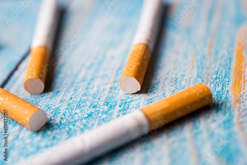 A closeup of tobacco cigarette on blue wooden background with space. Junk lifestyle.