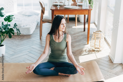 Attractive young woman doing yoga stretching yoga online at home. Self-isolation is beneficial, entertainment and education on the Internet. Healthy lifestyle concept.