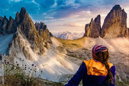 Sportive woman enjoys epic view from Sextner Stein on Monte Paterno and Tre Cime mountain range in the evening. Tre Cime, Dolomites, South Tirol, Italy, Europe. photo