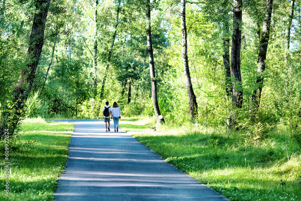 Fototapeta premium A young man and a woman walking in a park in summer.